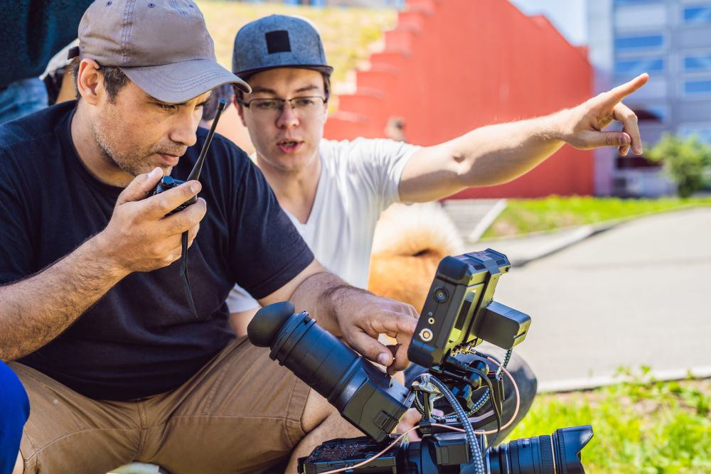 Dva člana filmske ekipe pored profesionalne kamere, jedan koristi radio-vezu, dok drugi pokazuje pravac snimanja